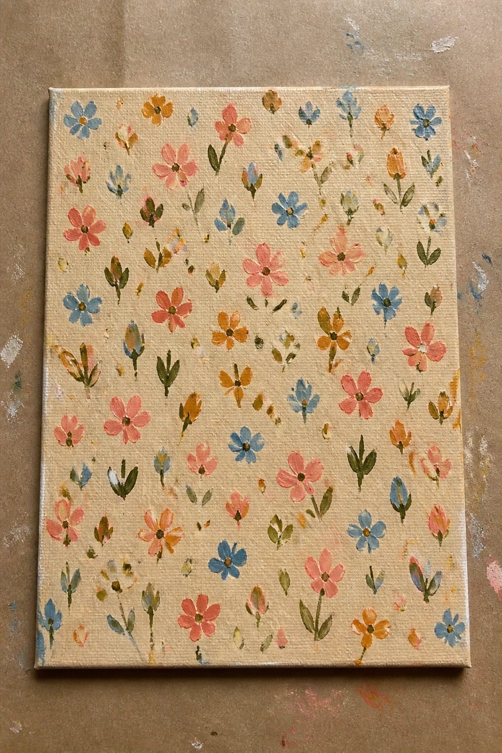 Canvas with scattered pink, blue, yellow, and orange flowers on beige background