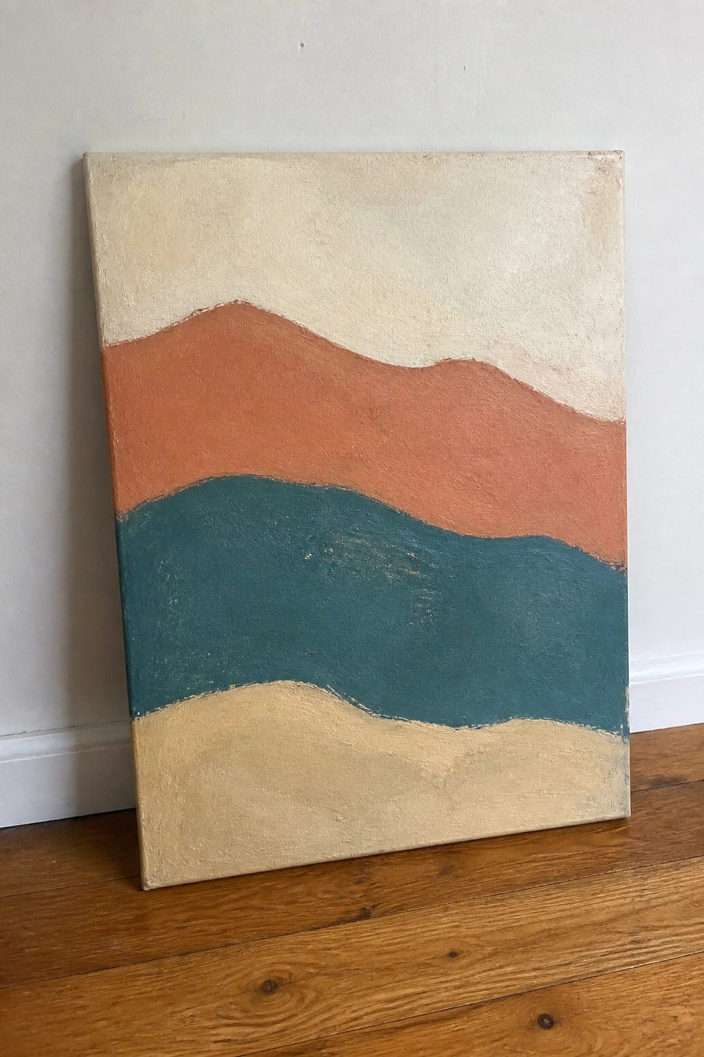 Abstract painting with wavy bands of cream, orange, teal, and beige leaning on wooden floor