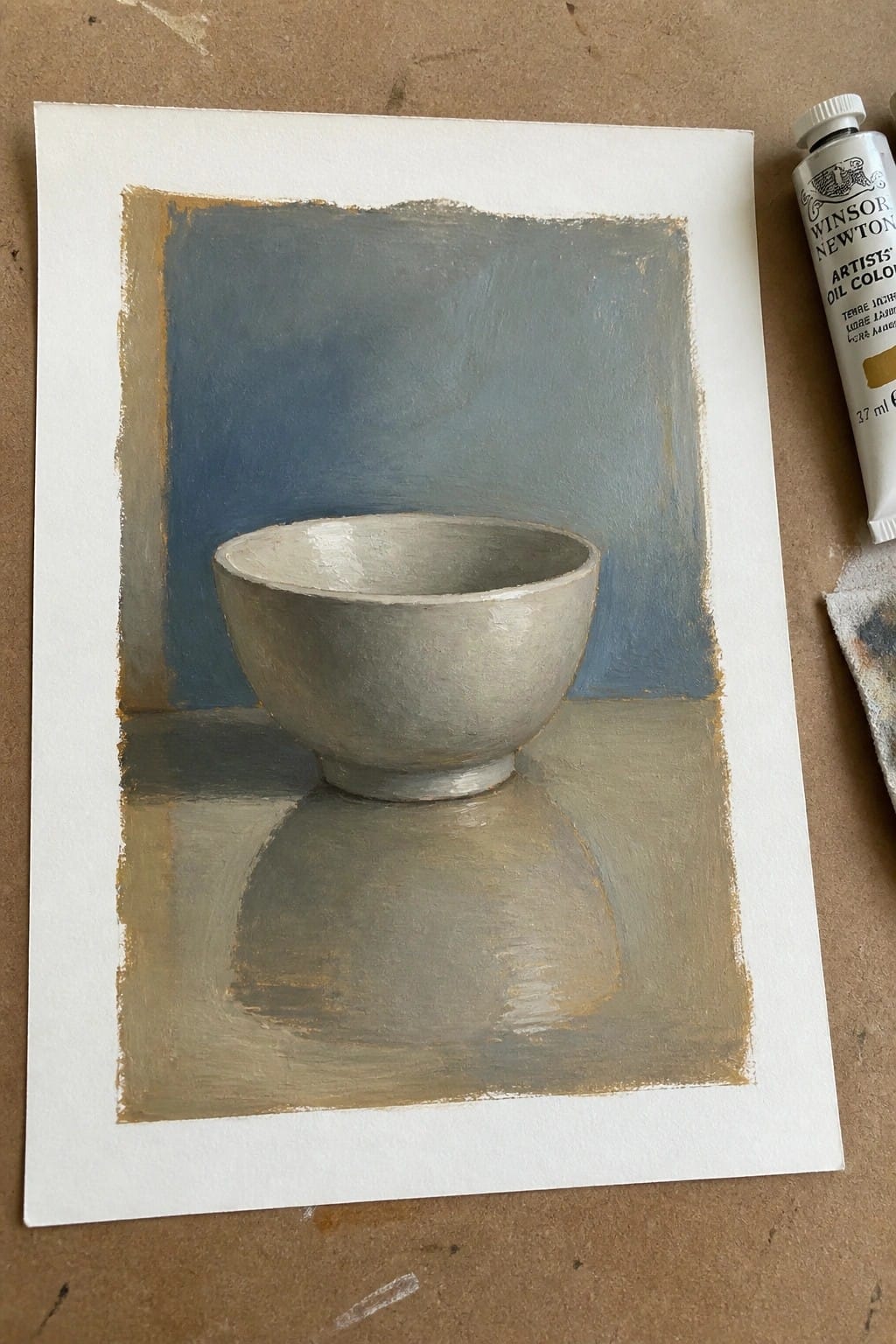 Oil painting of gray bowl on paper beside Winsor Newton terre jaune tube