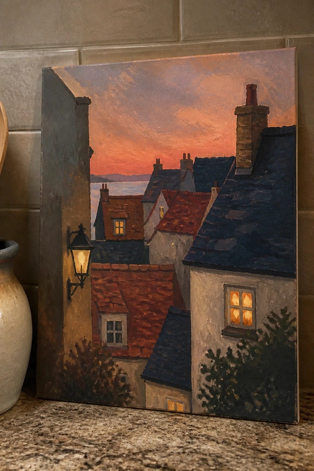 Painting of red sunset over village rooftops with glowing windows and distant sea