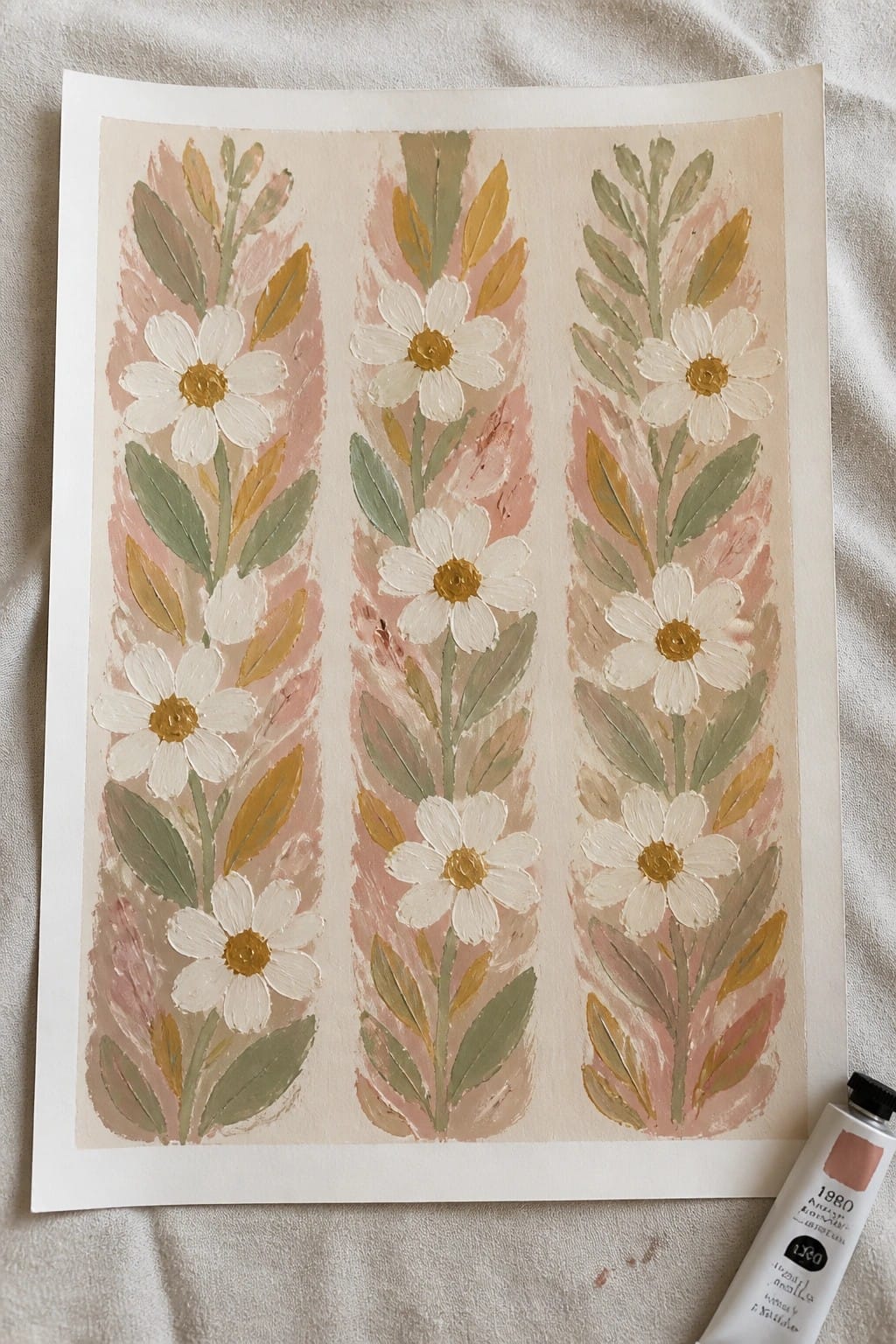 Three vertical panels of white daisies with yellow centers and mixed green and brown leaves on a light beige background, with a tube of paint visible in the corner.