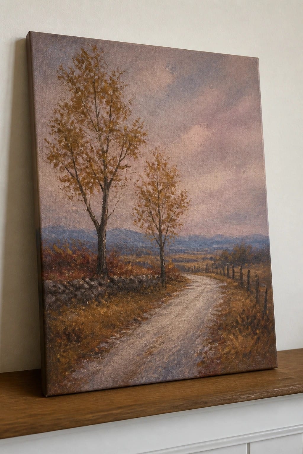 Autumn landscape painting with winding dirt road, trees, and mountains on wooden shelf