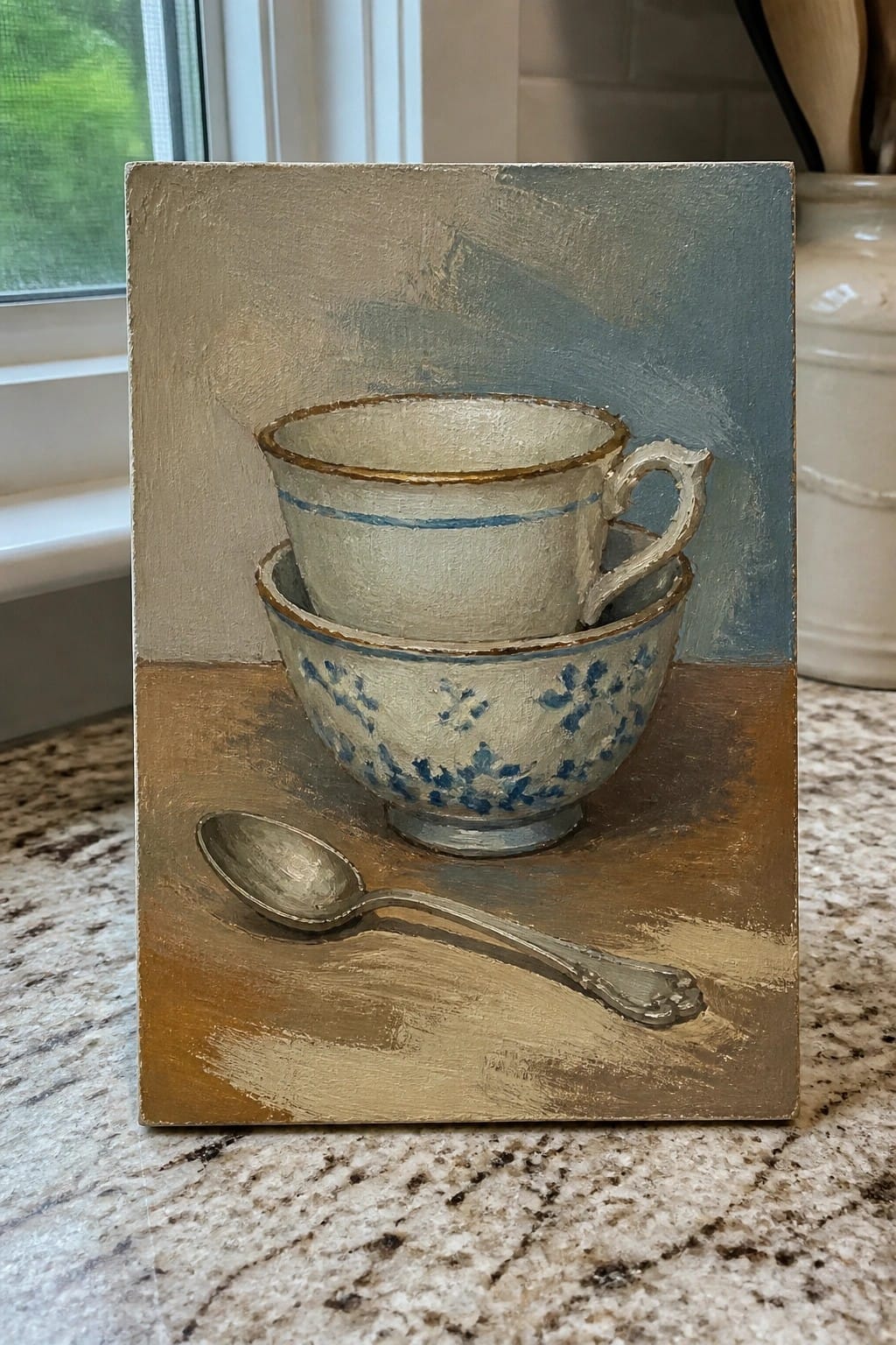 Still life painting of stacked blue floral teacups with a silver spoon on brown surface.