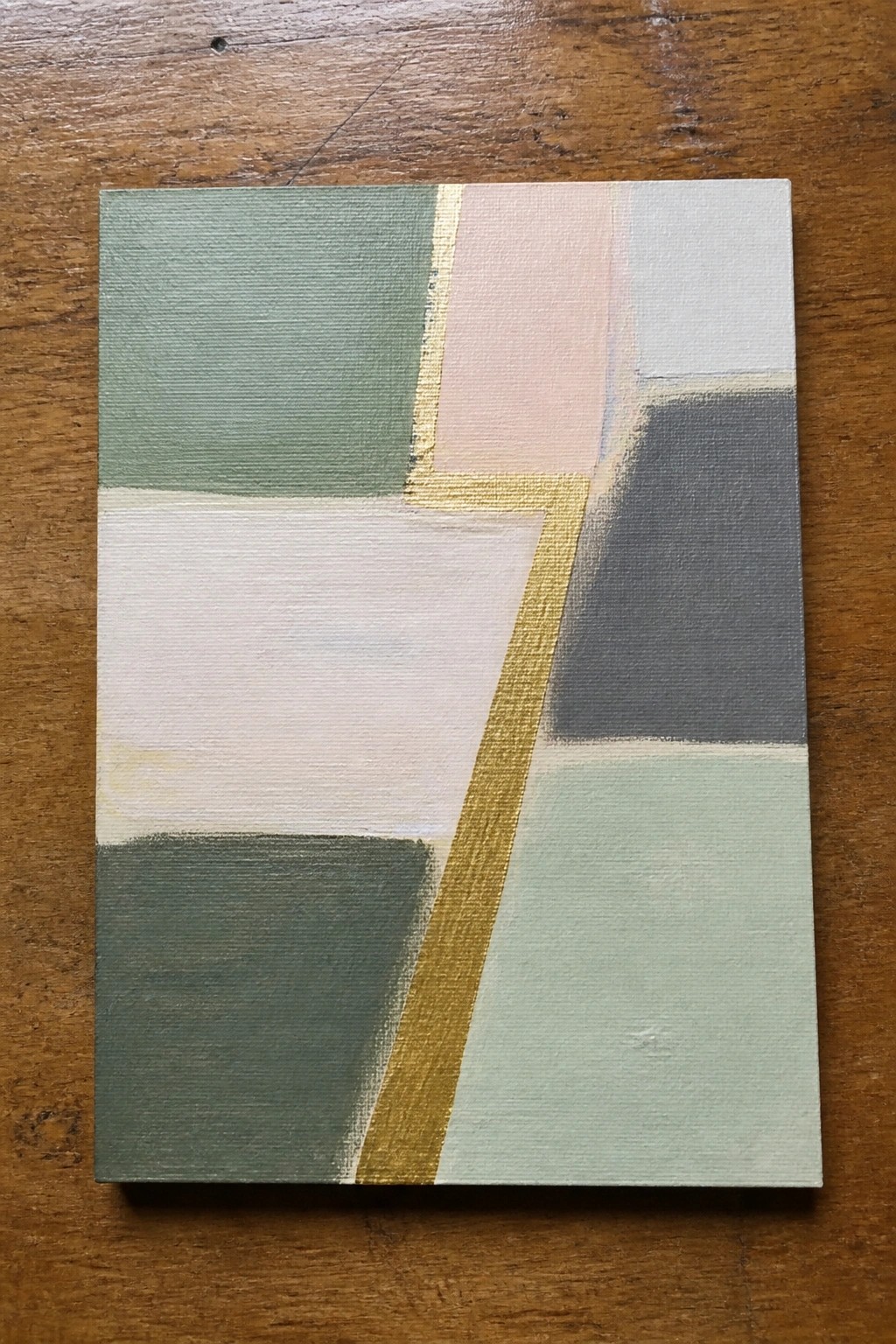 Abstract geometric painting with muted greens, pinks, grays, whites and gold lines on wood