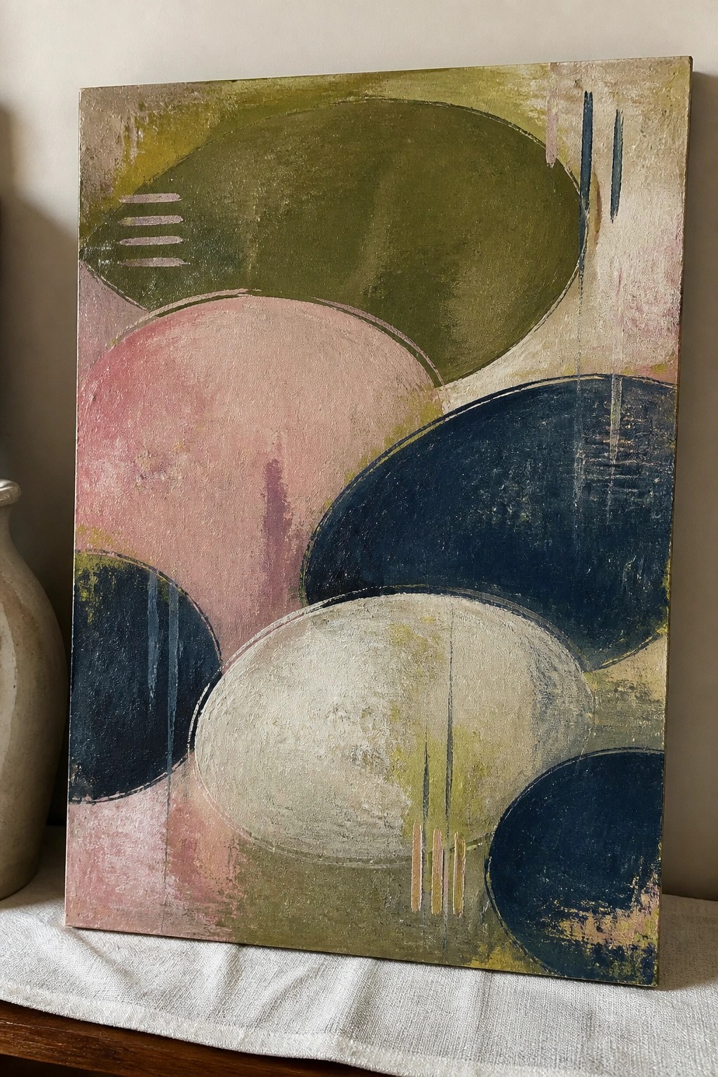 Abstract painting with overlapping circles in green, pink, navy, and beige tones on canvas