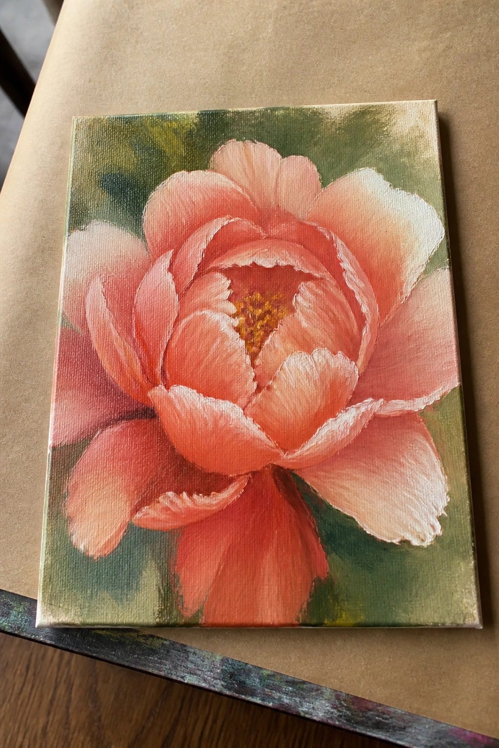 Oil painting of a coral pink flower with layered petals on a green and yellow background.