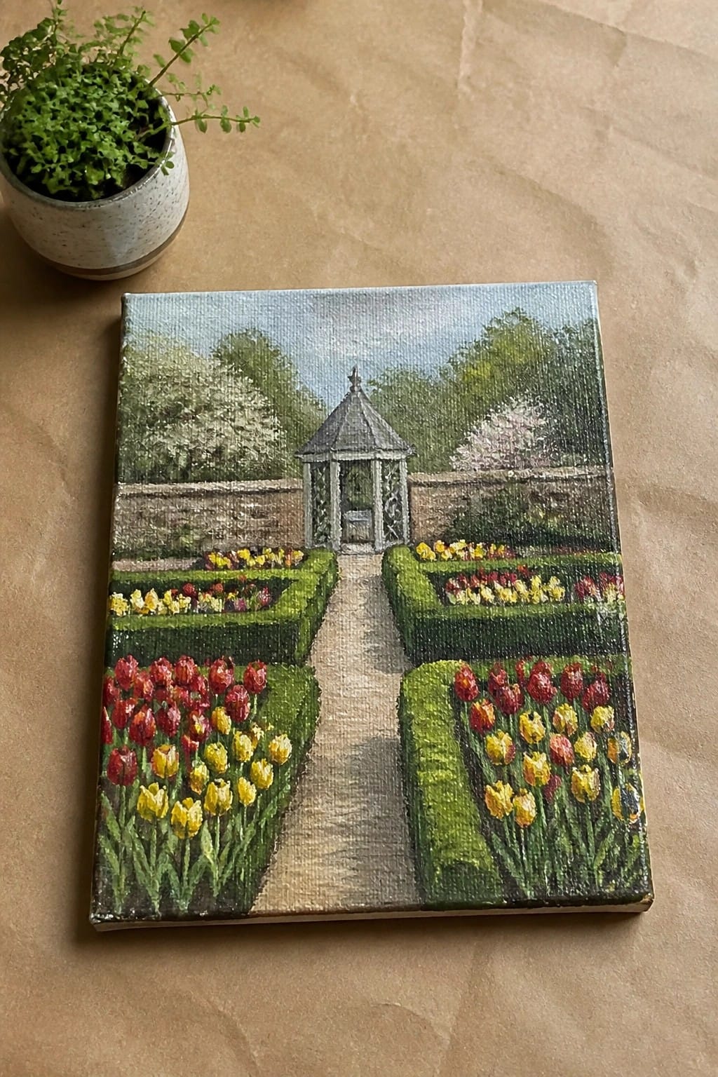 Canvas painting of tulip garden path leading to gazebo beside potted plant