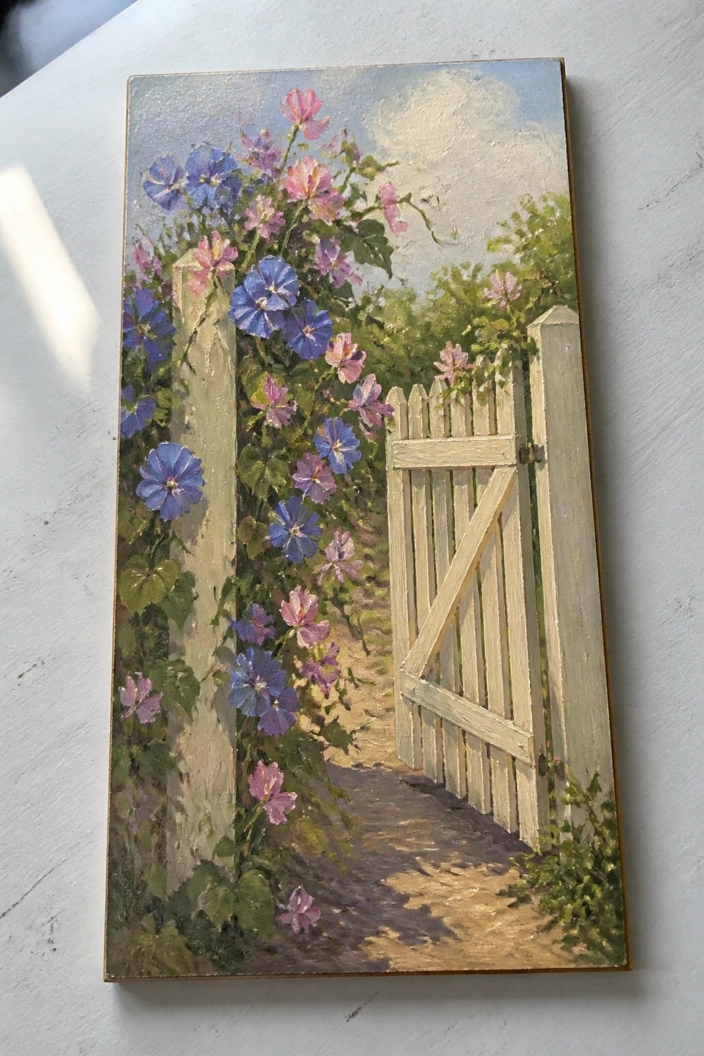 White wooden gate ajar amid blooming blue and pink morning glories on a path