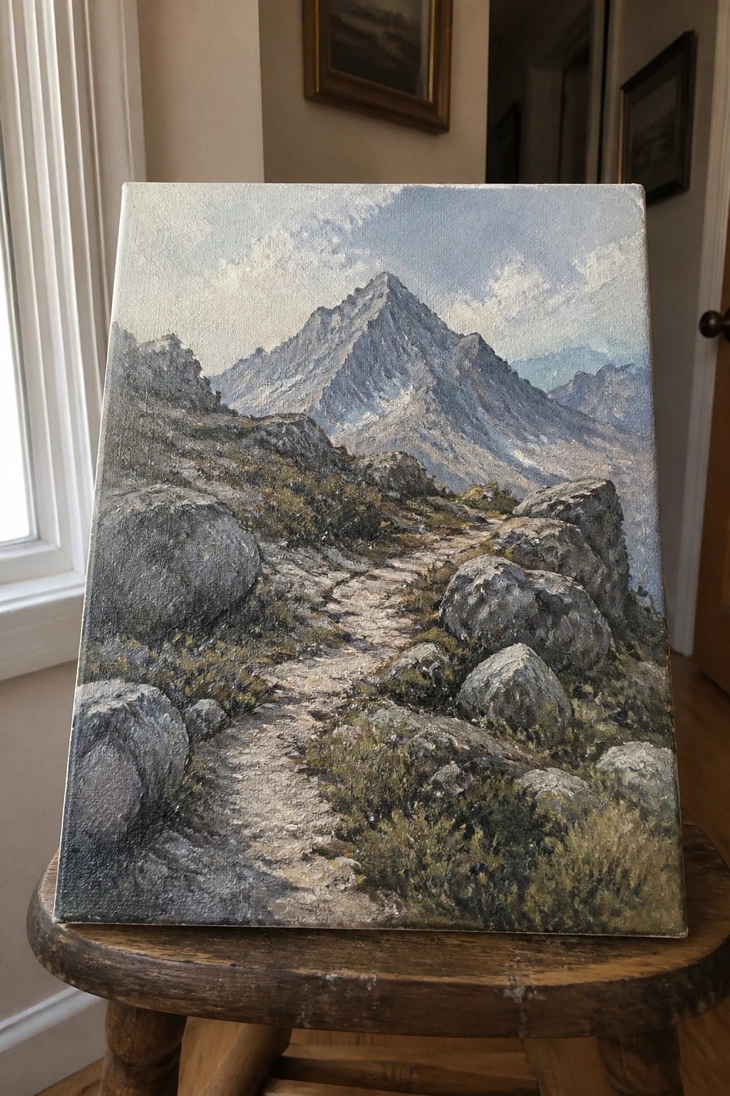 Realistic oil painting of rocky mountain trail to jagged peak on wooden stool