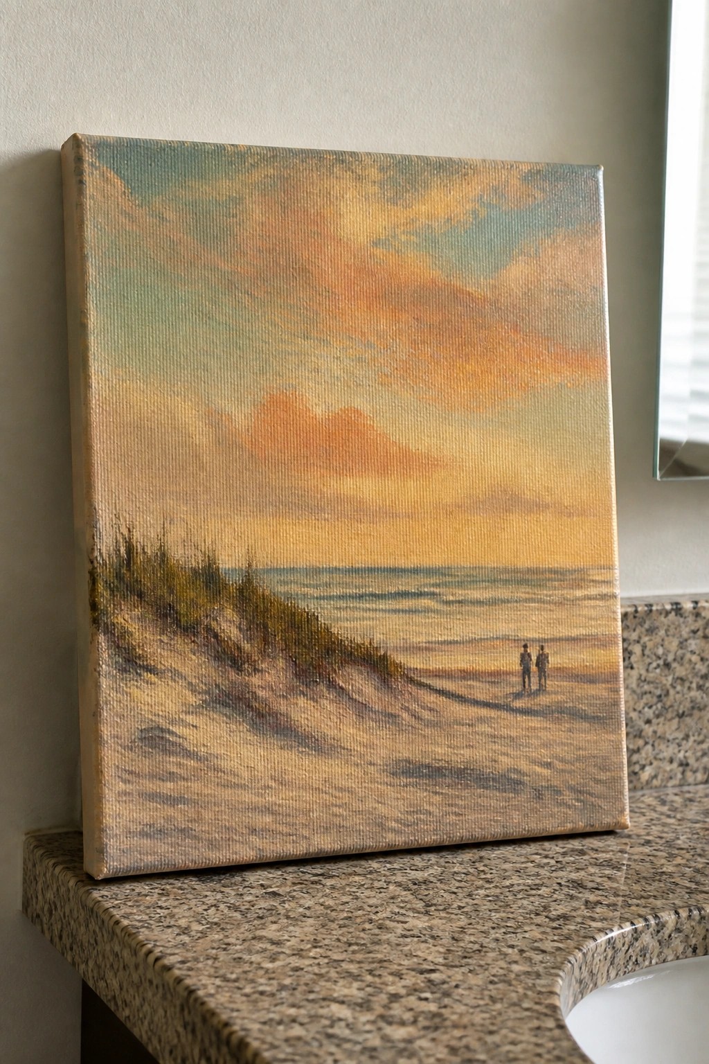 Canvas beach sunset painting with orange skies, dunes, waves and two figures on granite counter