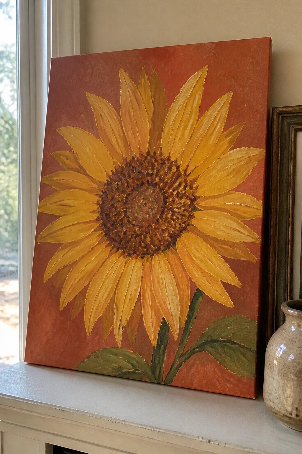 Yellow sunflower painting on red background resting on white windowsill beside vase