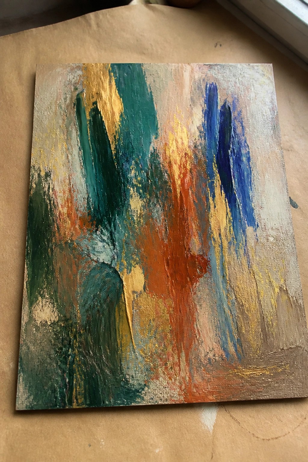 Square abstract oil painting with vertical streaks of teal green, gold, orange, and blue on a textured mixed background.