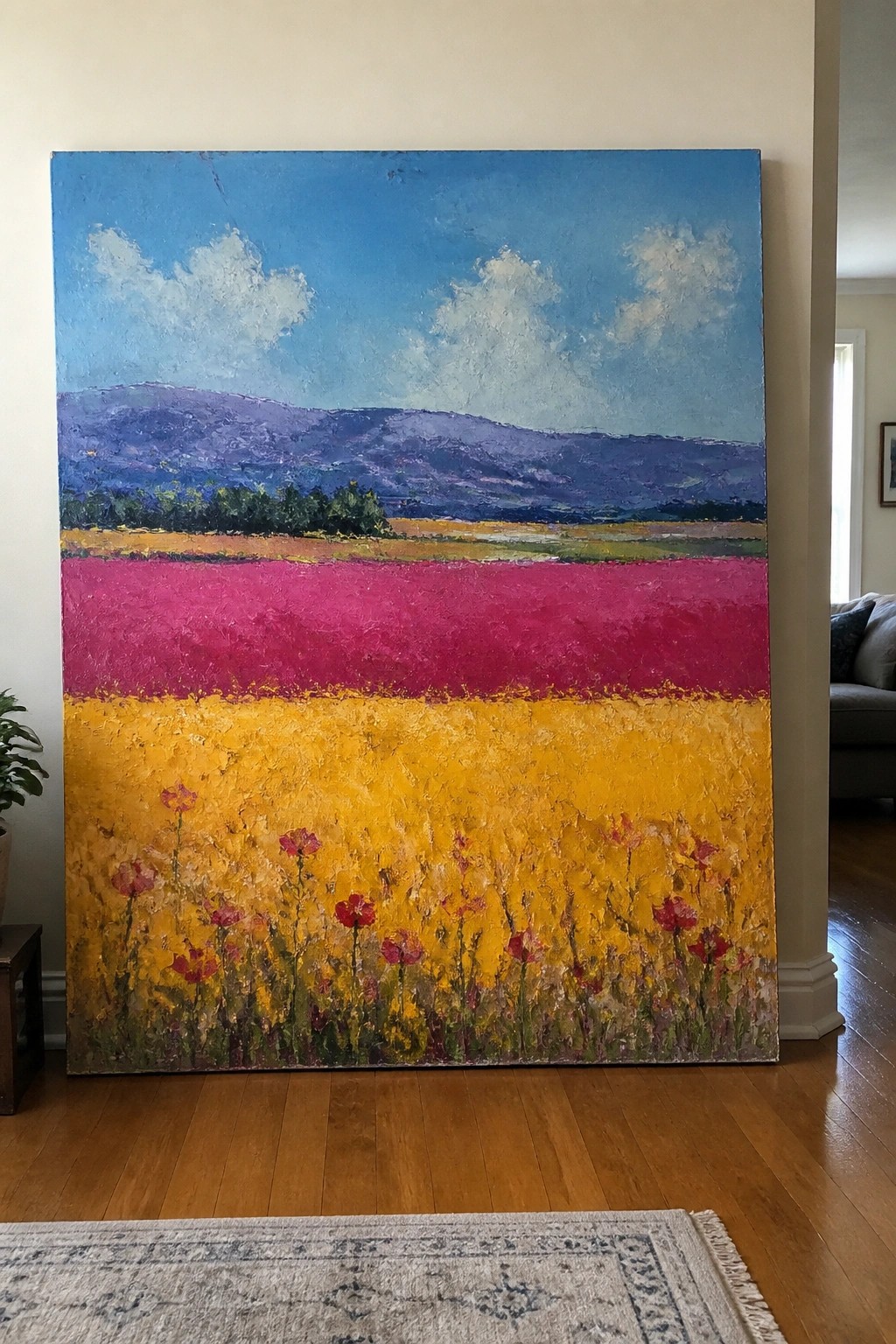 Oil painting of a landscape with blue sky and clouds, purple hills, a magenta band, and a yellow poppy field in the foreground.