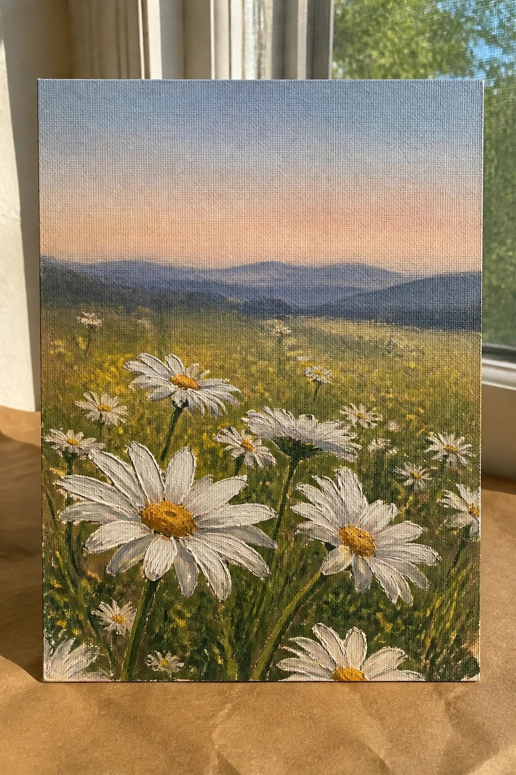 White daisies in meadow with distant mountains under pink-orange sunset sky on canvas