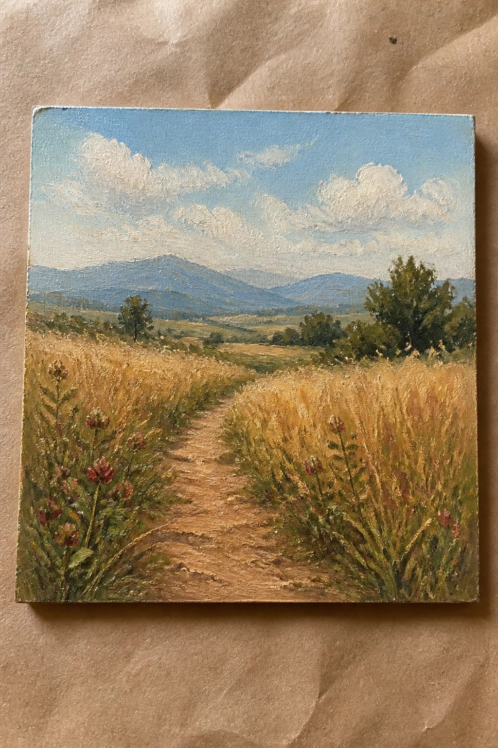 Oil painting of a dirt path through golden fields with red wildflowers and distant mountains.
