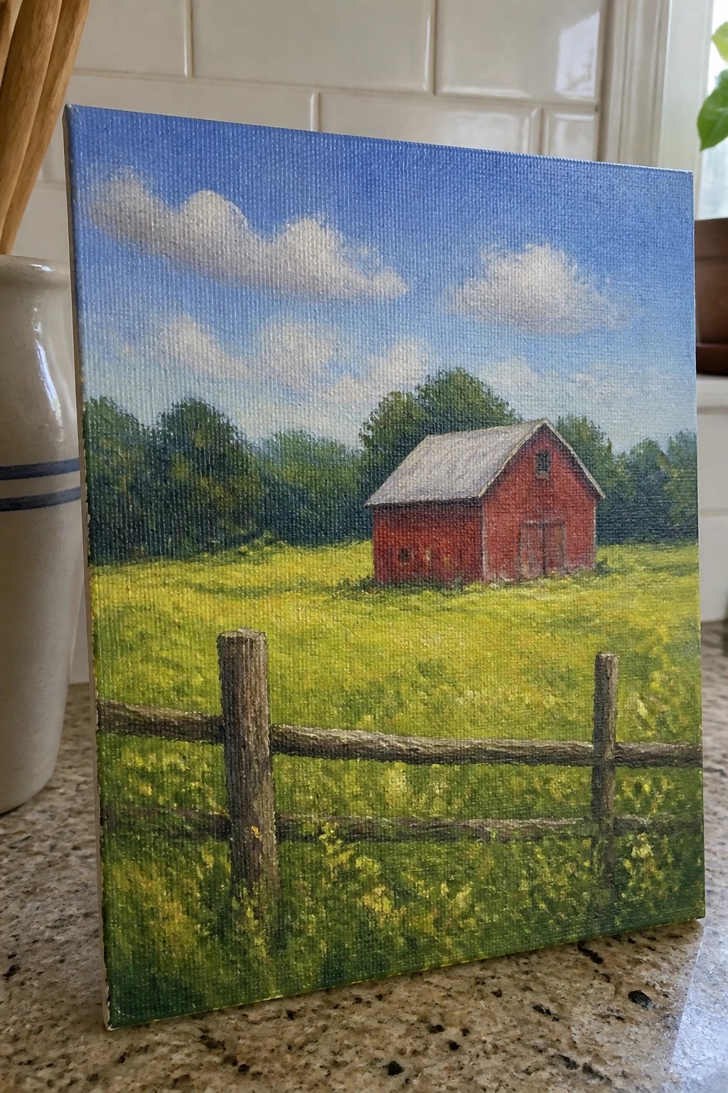 Painting of red barn in green field with wooden fence under blue sky with clouds.