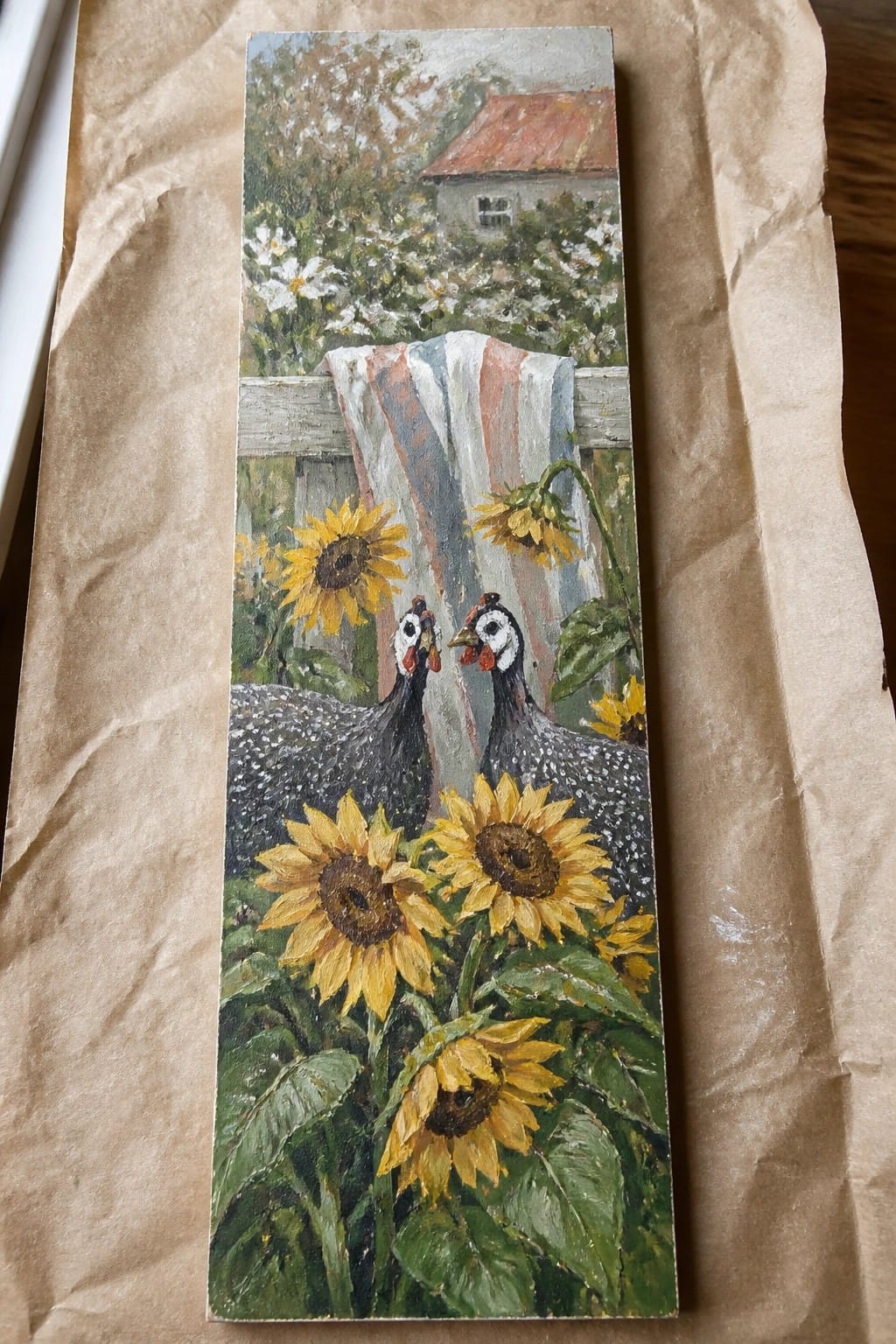 A vertical oil painting shows two black-and-white speckled birds among yellow sunflowers in front of a wooden fence with a striped cloth, and a house with a red roof in the background.
