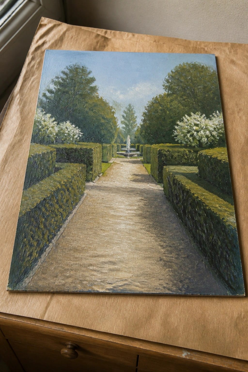 Oil painting of formal garden path lined with hedges leading to fountain on wood