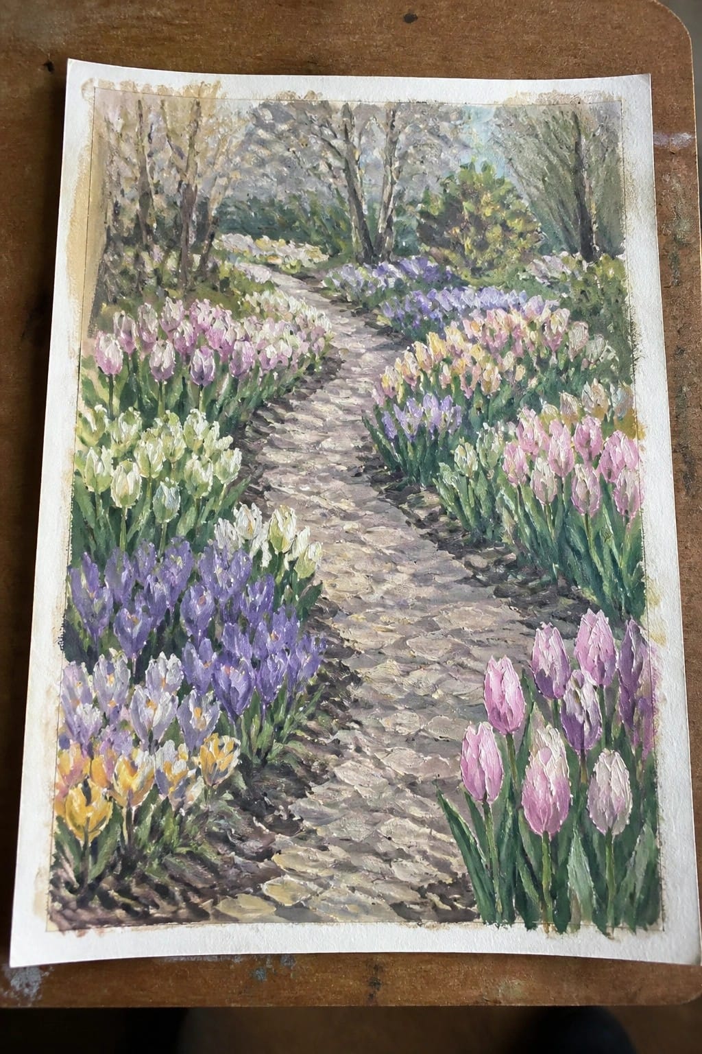 Watercolor painting of a cobblestone path lined with colorful tulips and spring flowers.