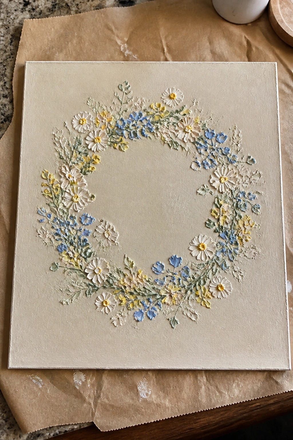 Textured floral wreath in white, yellow, and blue on beige square canvas