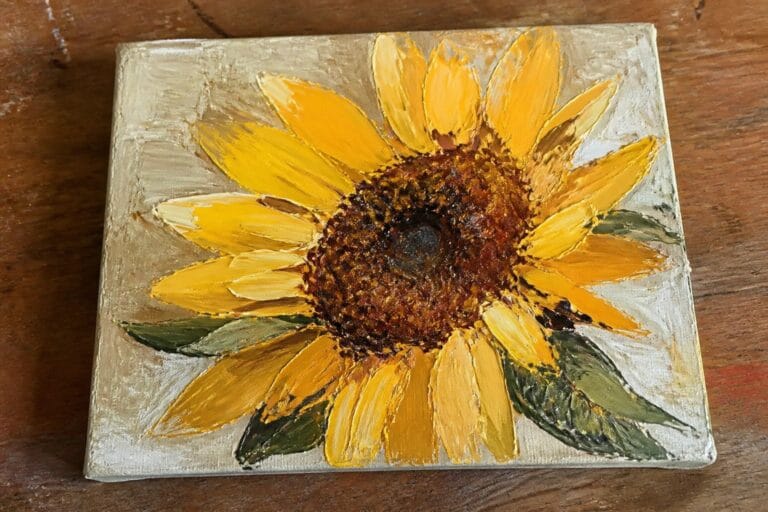 Impasto painting of a sunflower with thick yellow petals, brown center, and green leaves