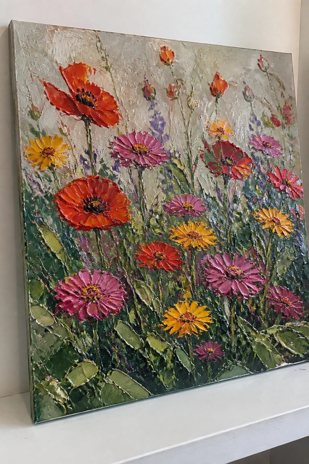 Vibrant impasto painting of red poppies, pink zinnias, and yellow flowers with green leaves.