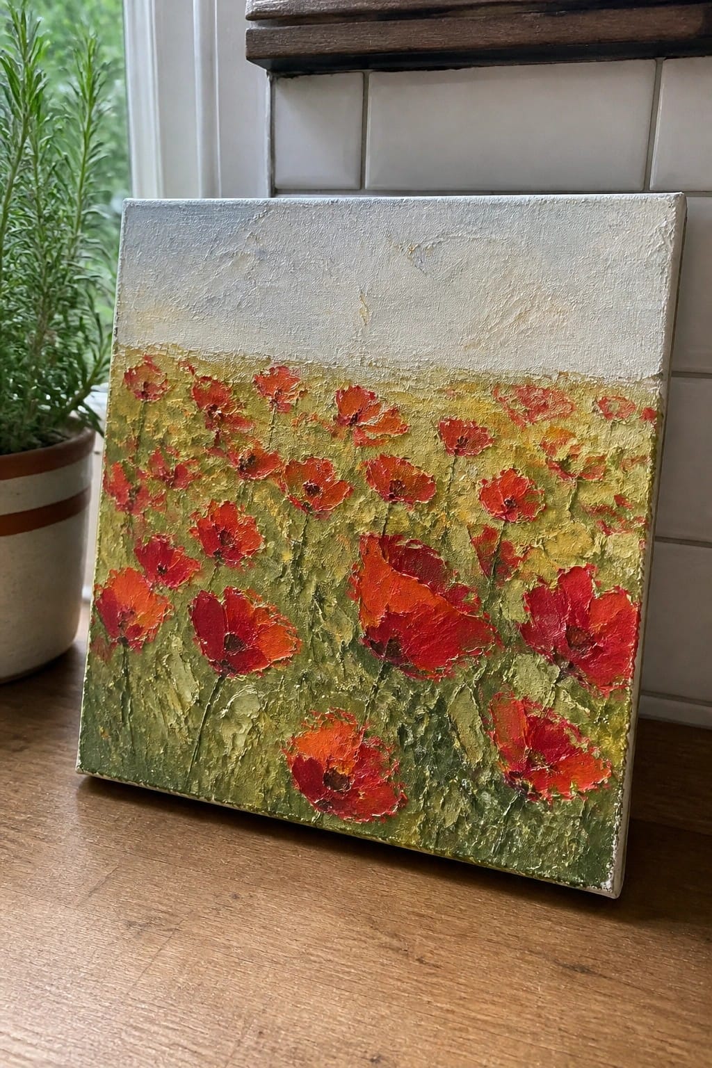 Thickly textured painting of red poppies blooming in a green and yellow field.
