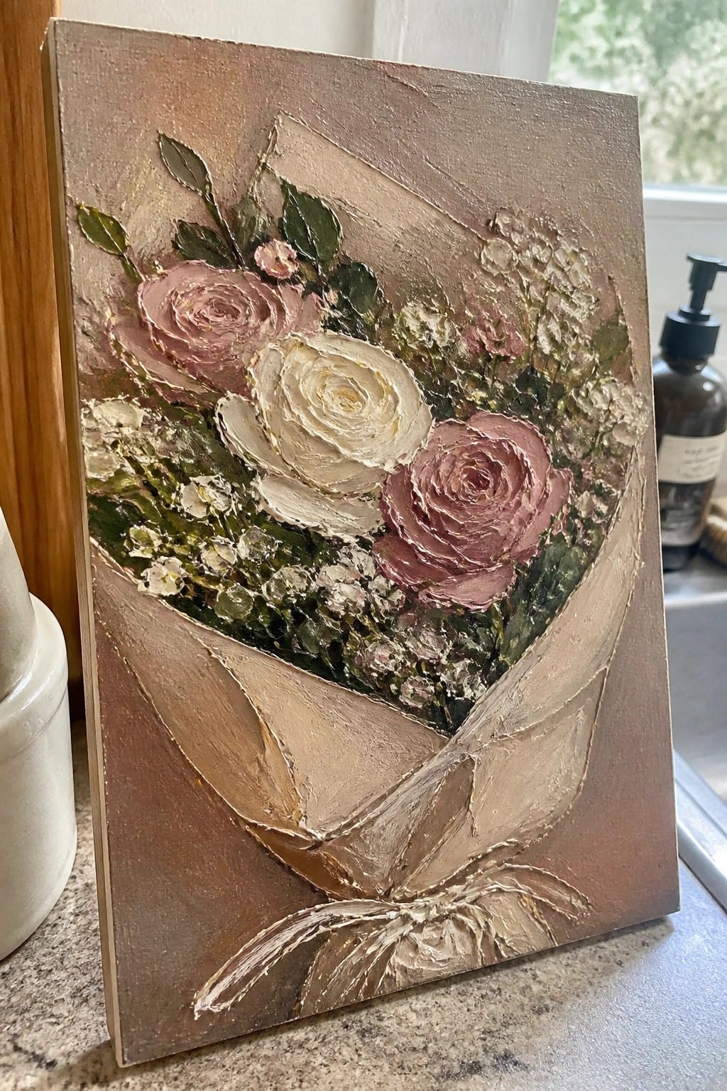 Thickly textured painting of pink and white roses in a brown paper bouquet with bow