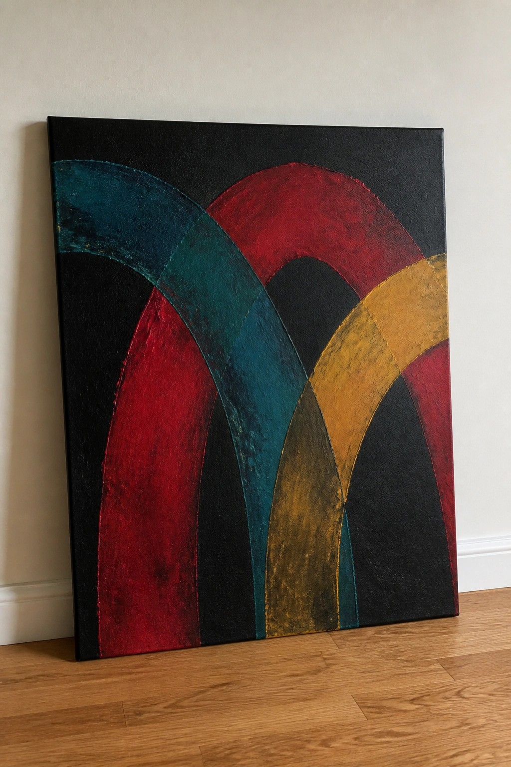 Abstract painting with arched red, teal, and yellow shapes on black canvas by wall
