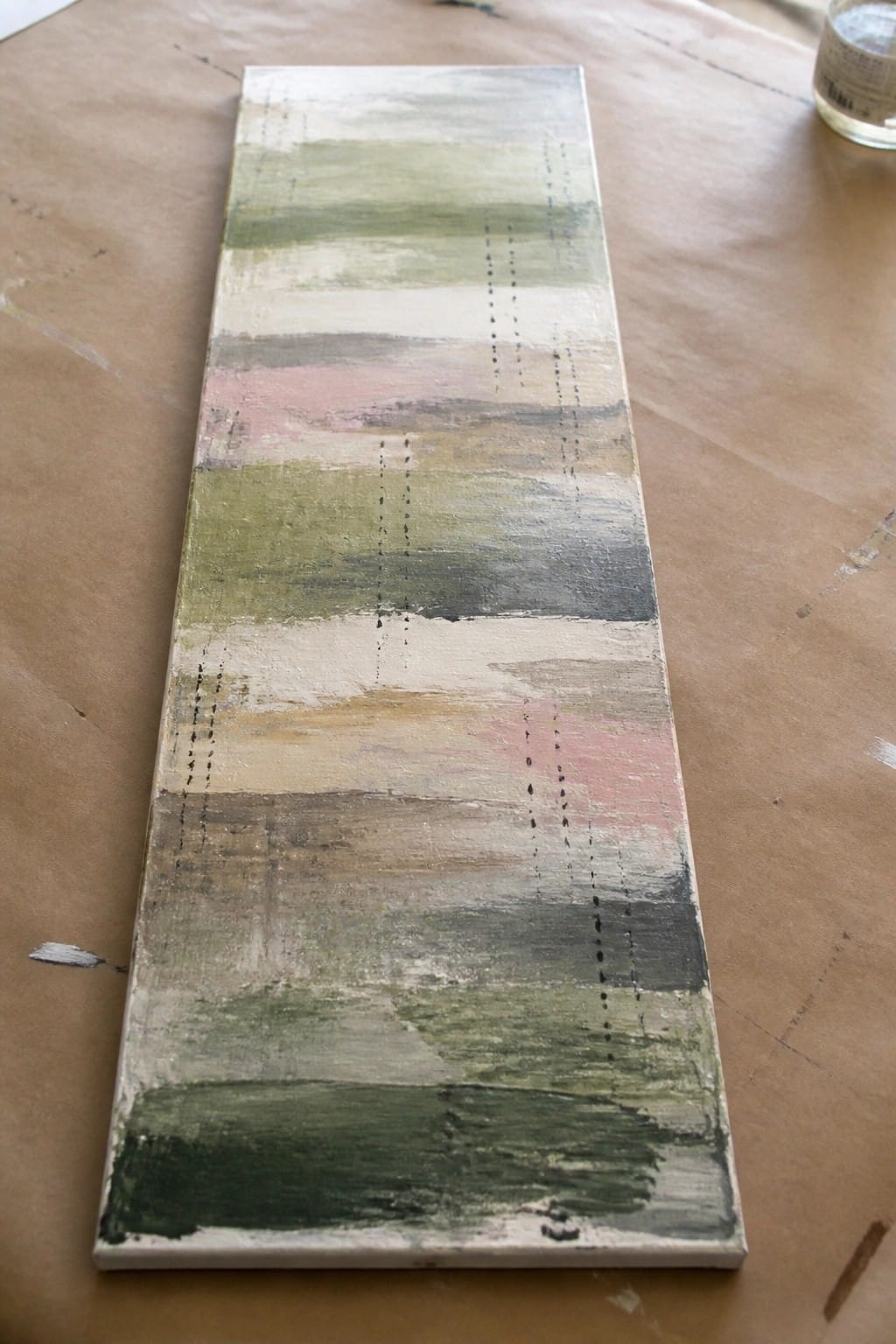Abstract canvas with horizontal green-pink-gray stripes and vertical black dotted lines on brown paper