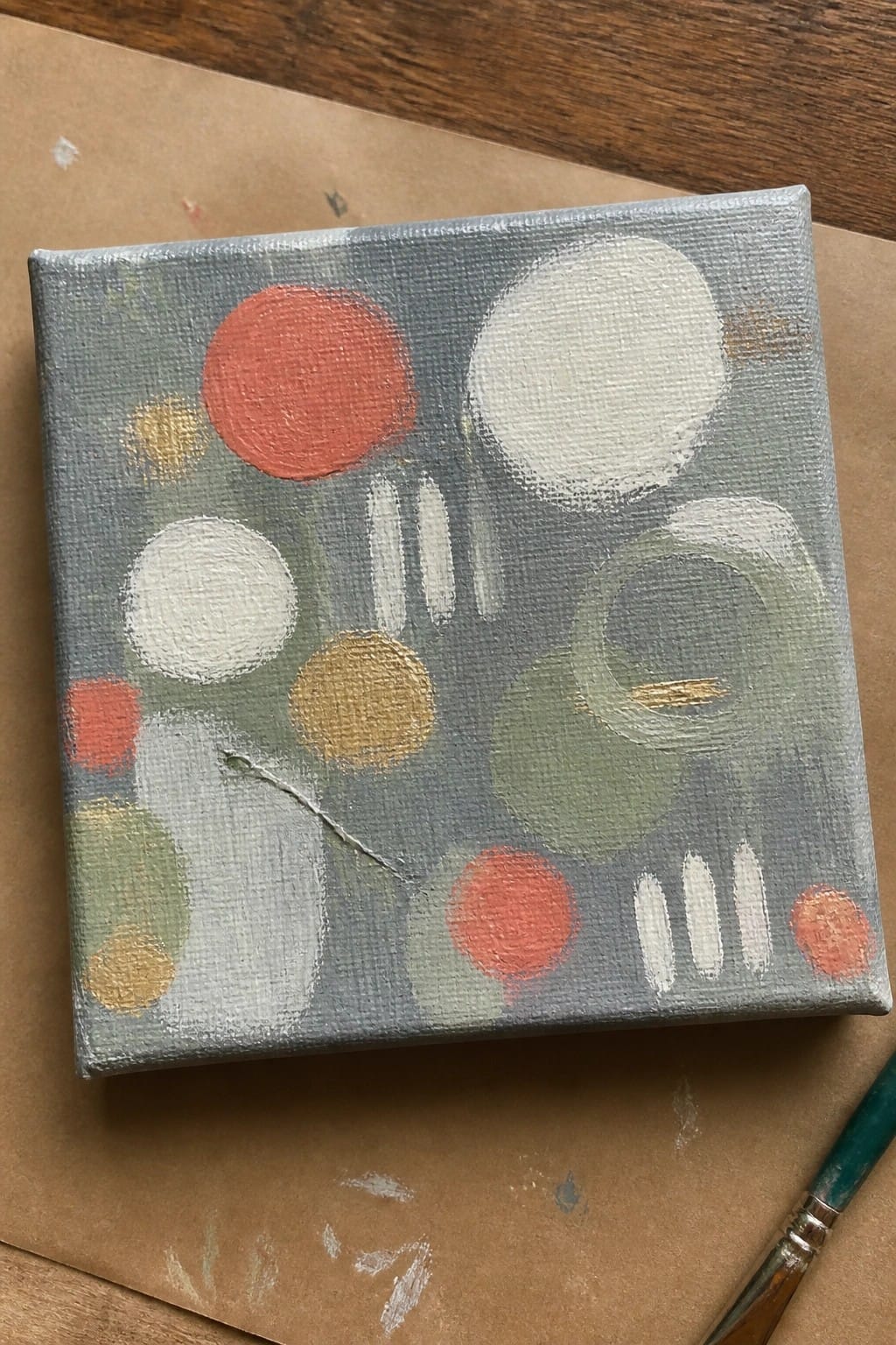 Abstract painting featuring red, white, gold, and green circles on blue-gray canvas.