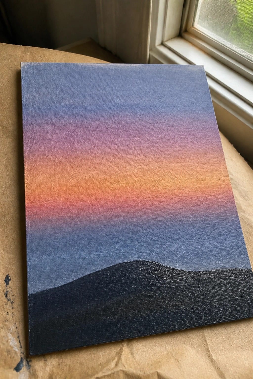 Canvas painting of blue-purple-orange gradient sky above black hilly silhouette near window