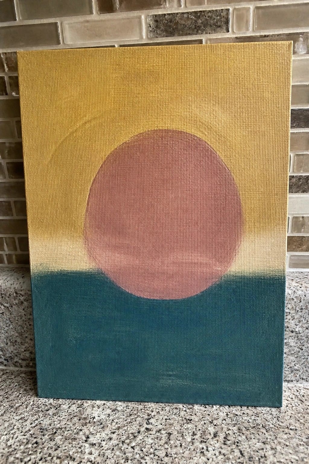Abstract canvas painting with large reddish circle on yellow-to-teal gradient background