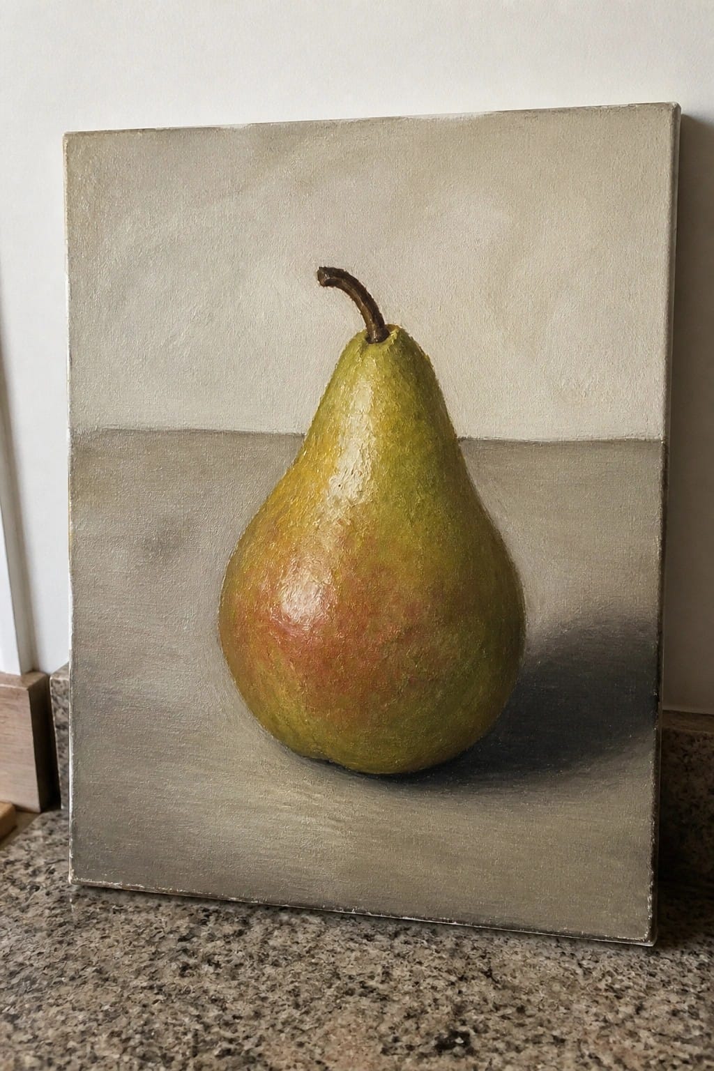Realistic painting of a green-yellow pear with red tones on gray canvas