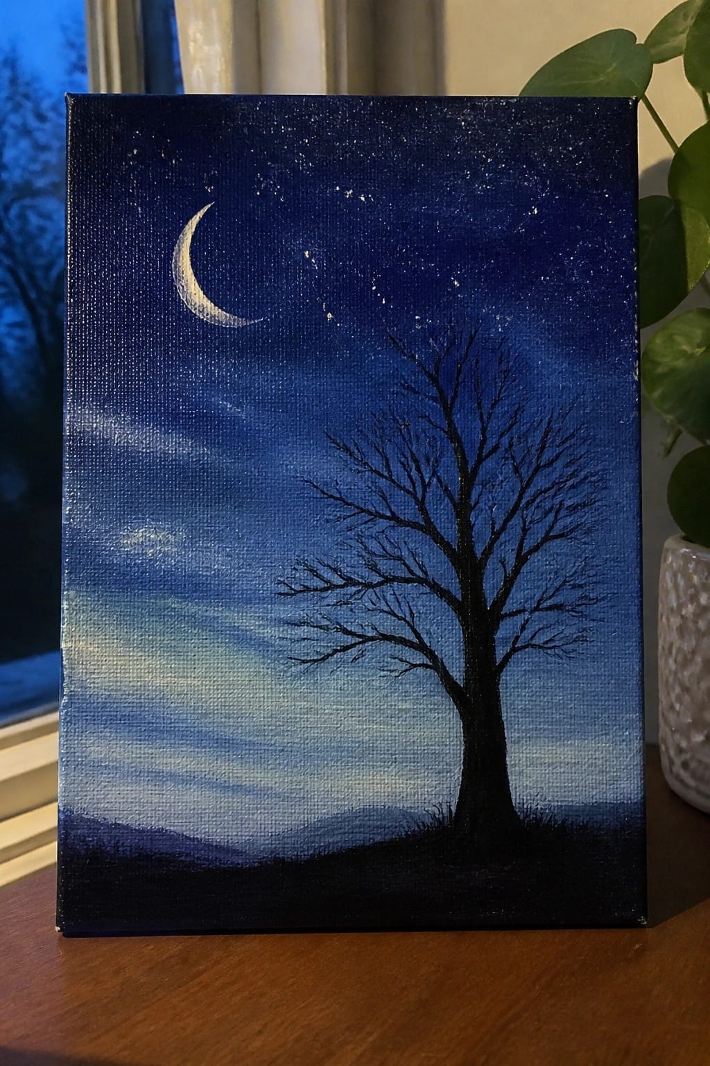 Crescent moon and stars above a silhouetted bare tree in blue night sky painting