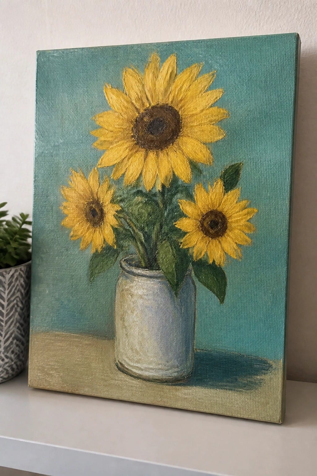 Three yellow sunflowers in a white vase on teal canvas painting.