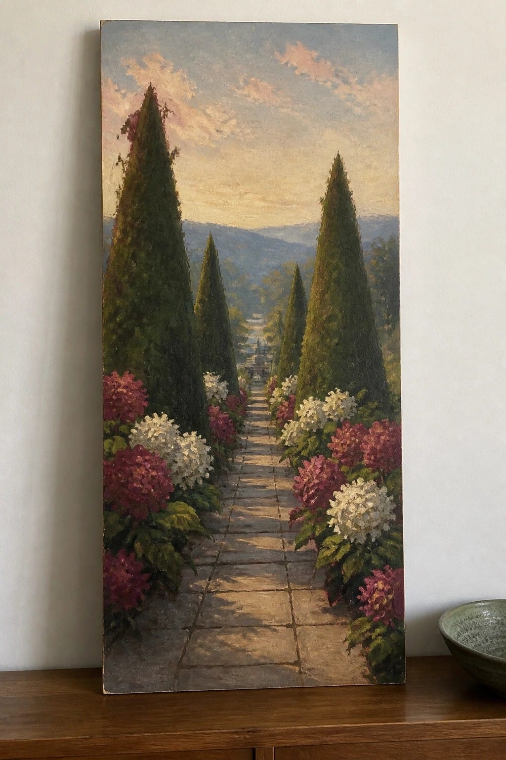 Sunlit stone pathway lined with tall cypress trees and blooming pink-white hydrangeas.