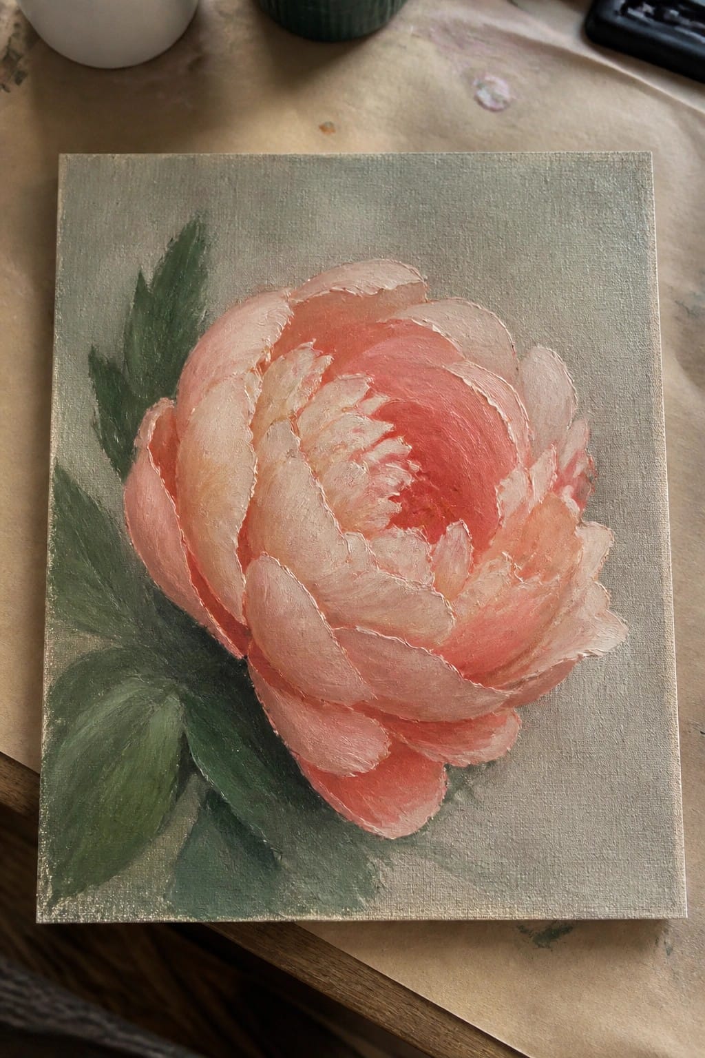 Textured painting of a blooming coral peony with layered petals and green leaves on canvas.