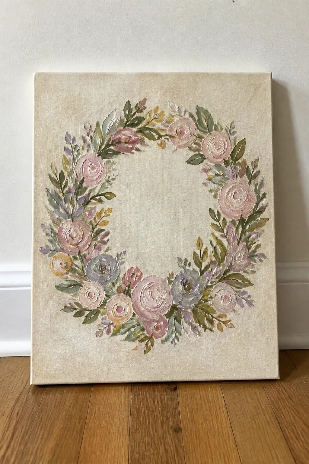 Painted floral wreath of pink roses and leaves on beige canvas against wood floor