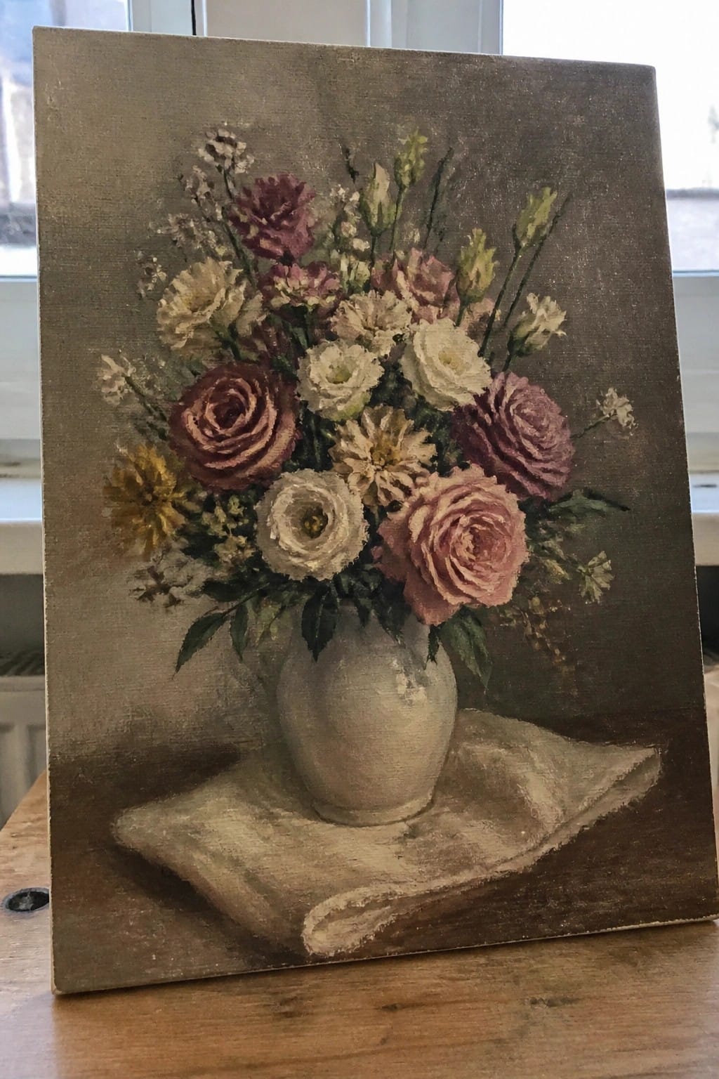 Still life of pink roses and flowers in white vase on draped cloth