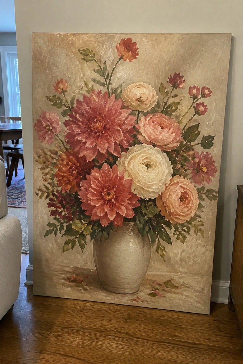 Large painting of pink dahlias and roses in beige vase on wooden floor