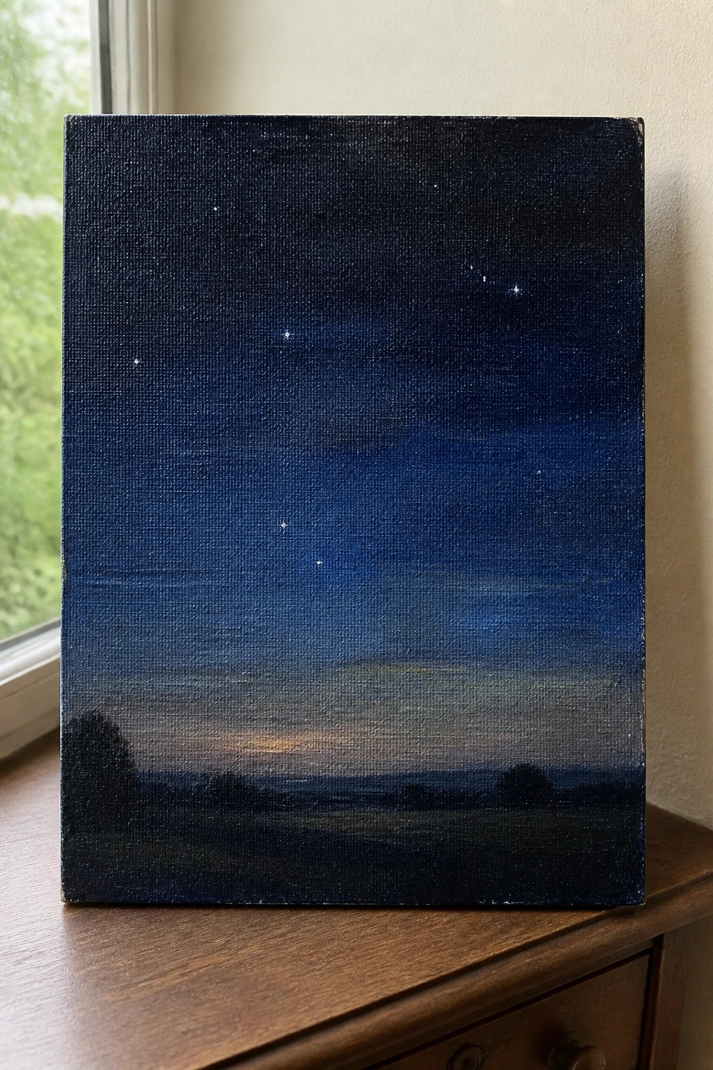 Starry night sky painting with stars and silhouetted landscape on wooden dresser
