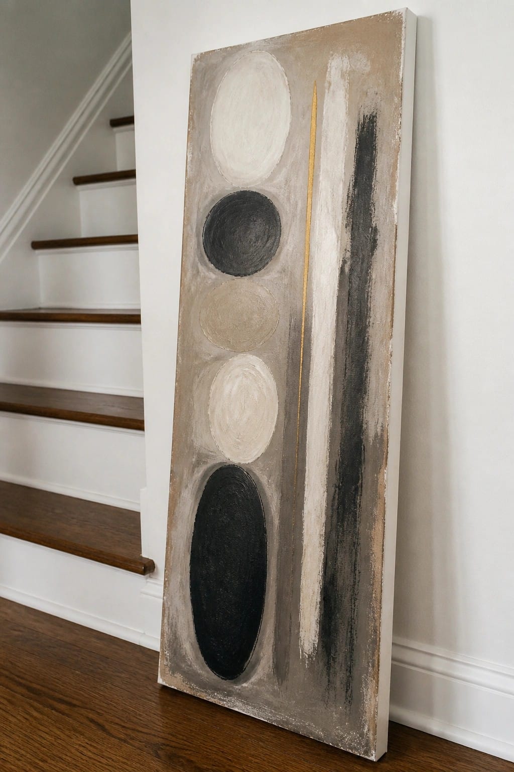 Abstract painting with stacked circles, black oval, gold line, and stripe beside stairs.