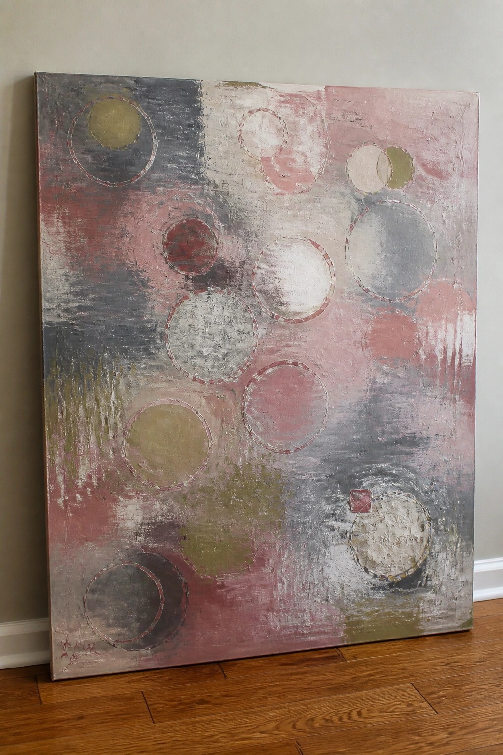 An abstract oil painting on canvas with overlapping circles in muted pink, gray, red, and olive against a heavily textured background.