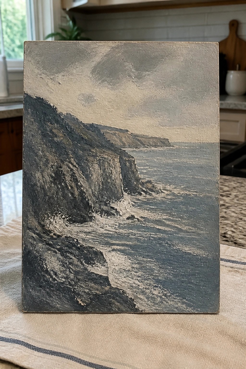 Textured painting of dark cliffs bordering a gray sea with whitecaps under cloudy skies