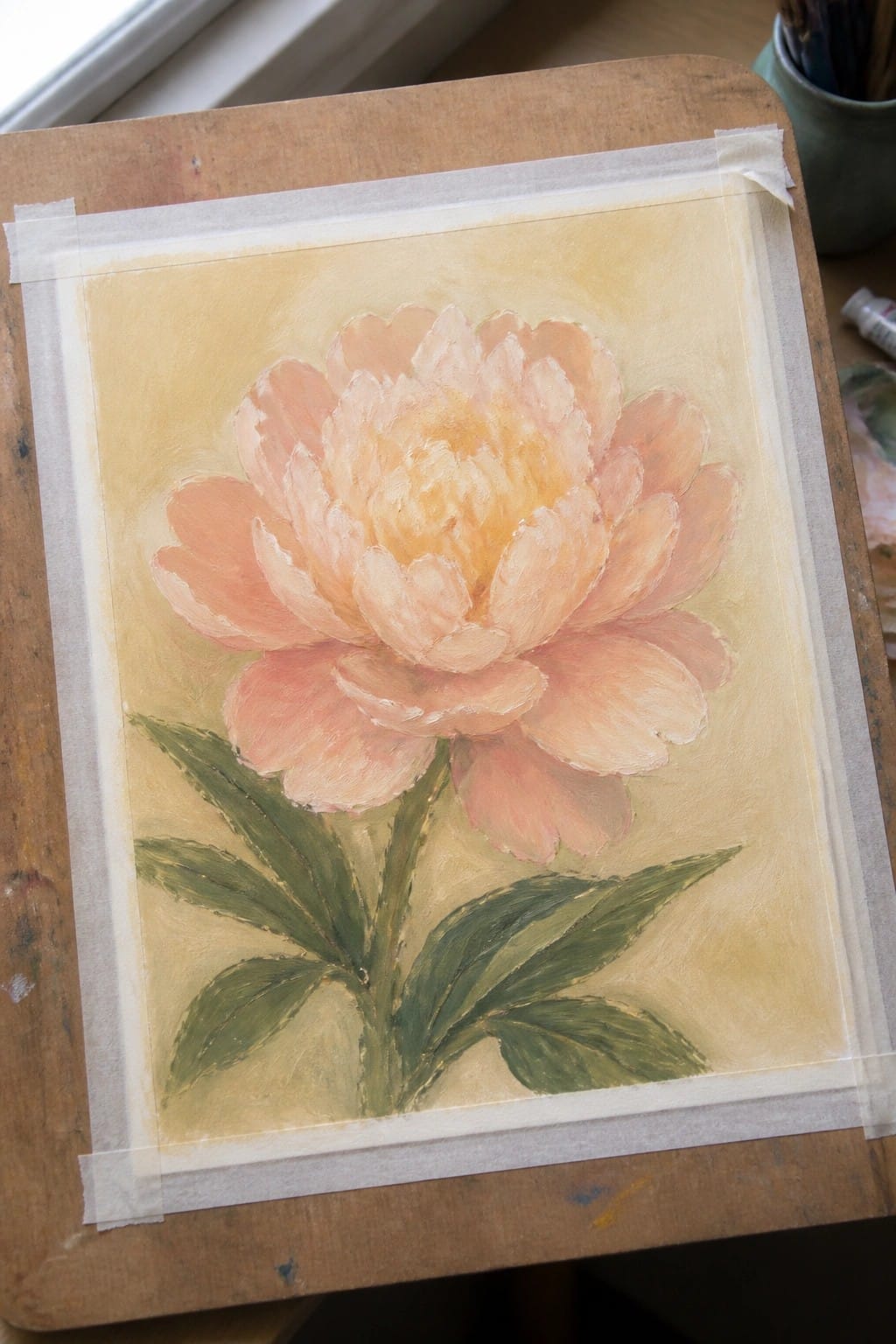 Peach peony flower painting with green leaves on yellow background, taped to wood