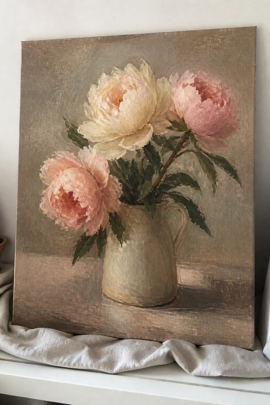 Oil painting of three pink peonies in a beige ceramic pitcher on canvas