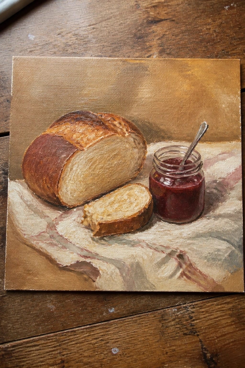 Still life painting of bread loaf, slice, and red jam jar with spoon on cloth.