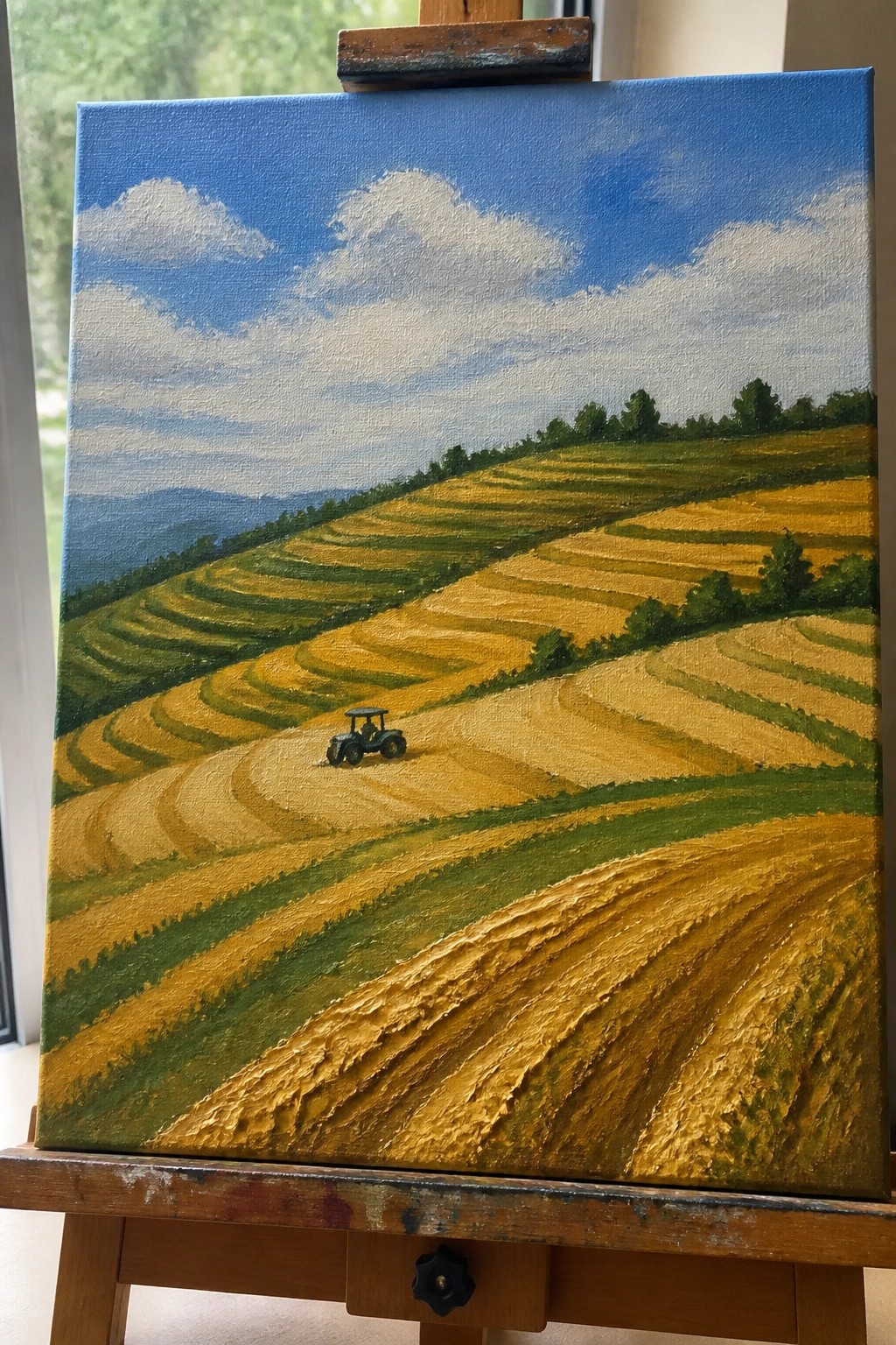 Oil painting on easel of golden terraced fields with tractor under blue sky.