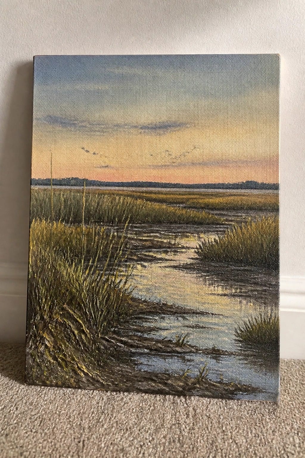 Painting of sunset over marsh with golden grasses, reflective water, and birds in flight